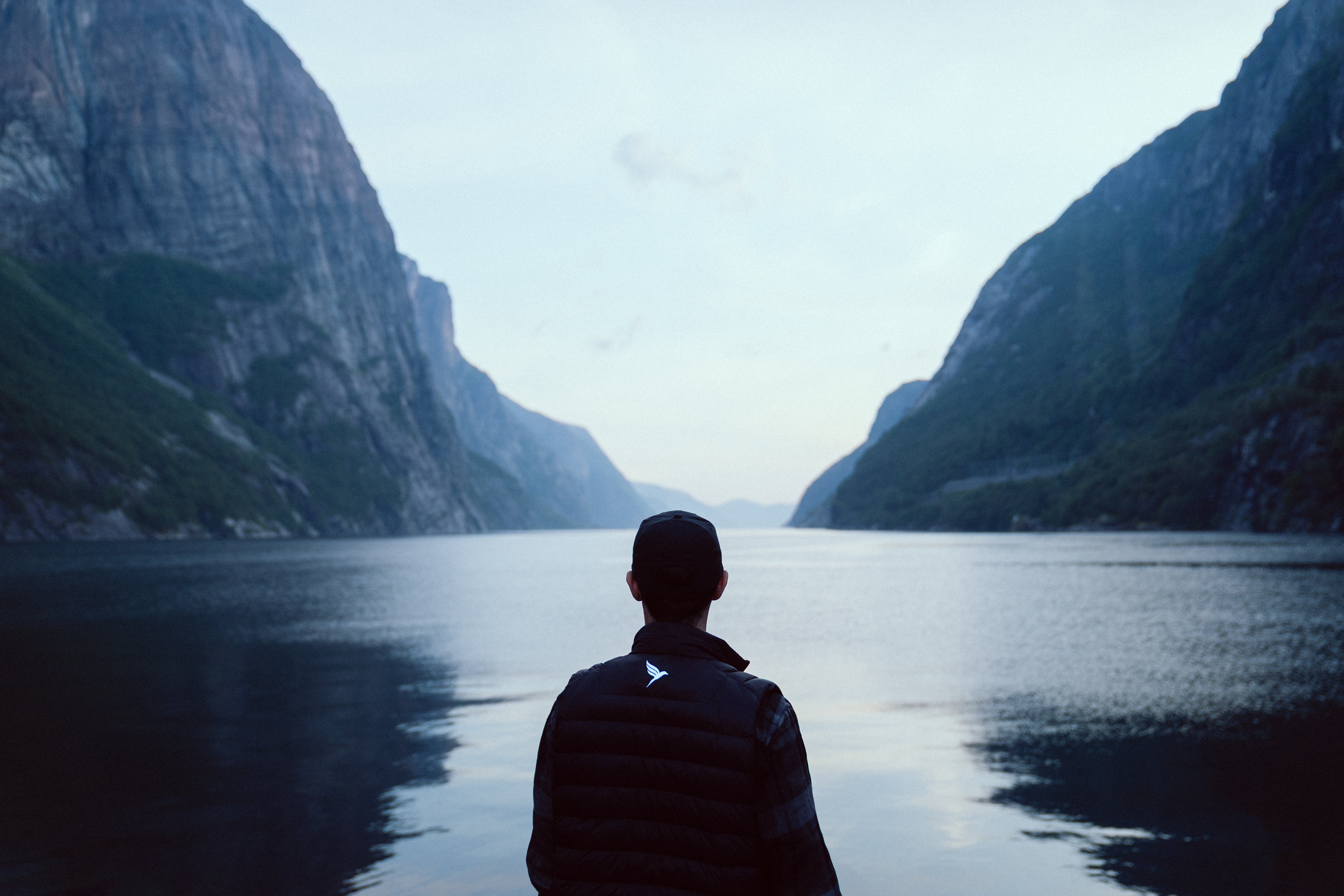 Person standing by a lake in a Koltrast heated vest with mountains in the background